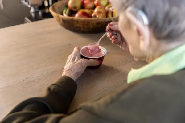 Vrouw eet toetje aan eettafel
